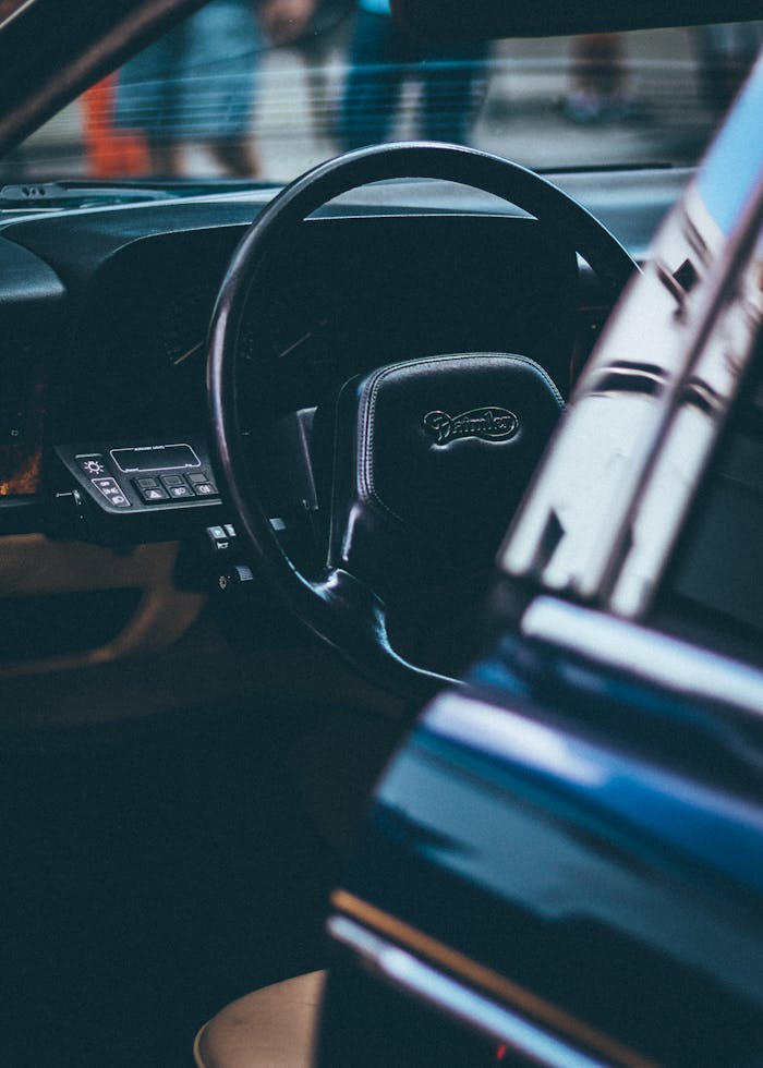 Close-up shot of a classic car interior focusing on the steering wheel and dashboard.