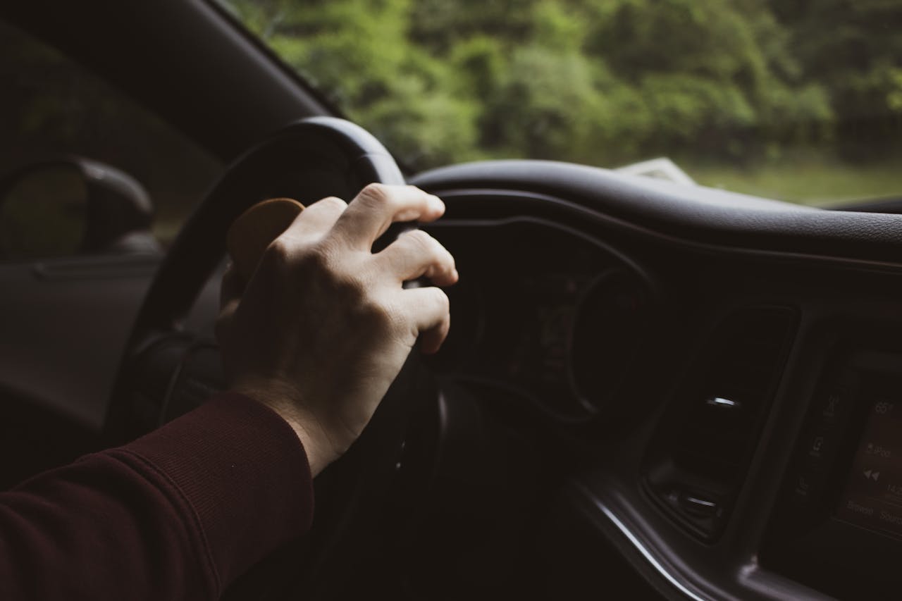 hero-about Close-up of a hand on a car steering wheel, depicting a relaxed driving moment.